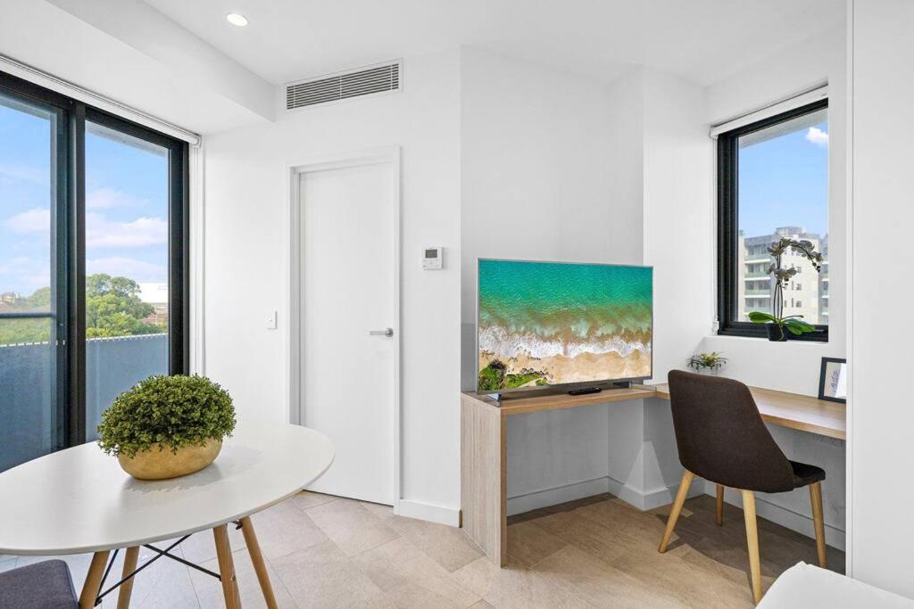 a white living room with a table and a tv at Lovely Studio apartments in Strathfield CBD in Sydney