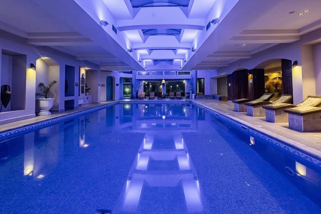 a swimming pool in a hotel with blue lighting at Мия 2 Deluxe Royal Spa in Velingrad