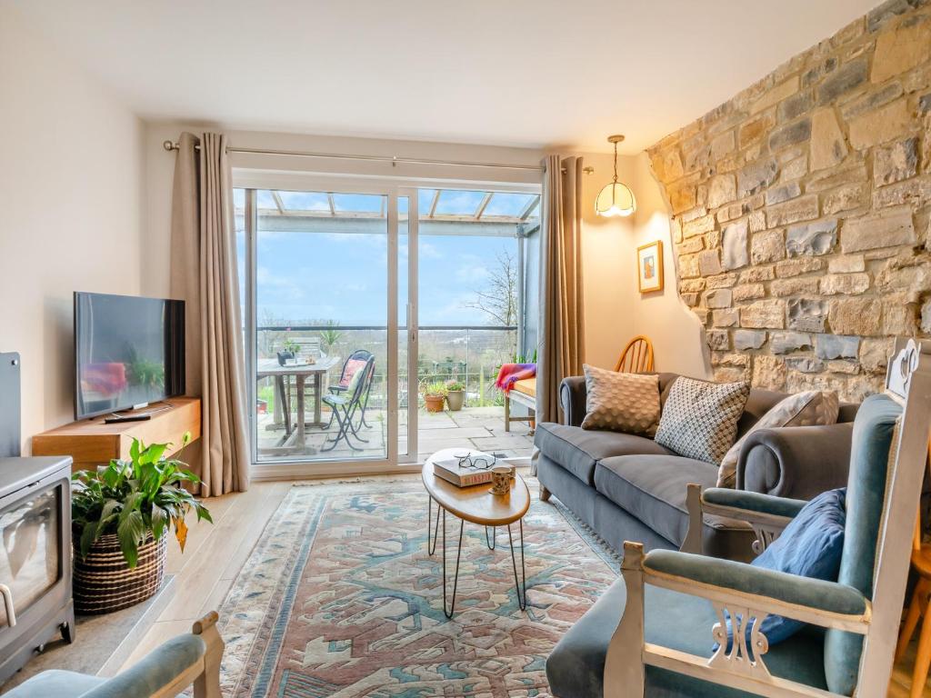 a living room with a couch and a stone wall at Hide On The Hill in Theale