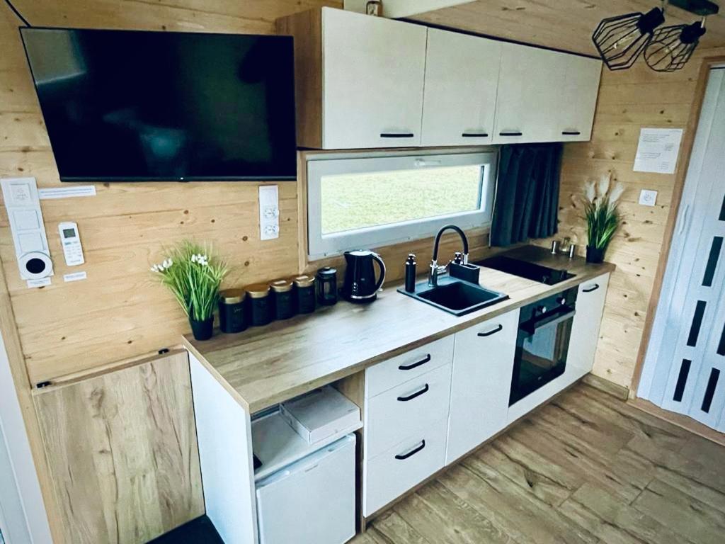 kuchnia ze zlewem i telewizor w przyczepie kempingowej w obiekcie Tiny House Village (850m od Suntago) w mieście Grabce