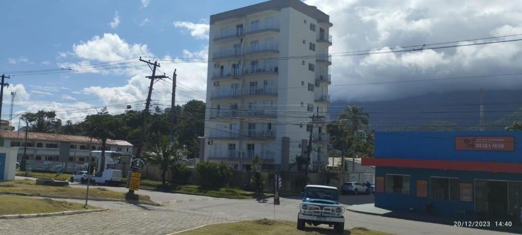 un grand bâtiment blanc avec une voiture garée devant. dans l'établissement Riviera Massaguaçu 23, à Caraguatatuba