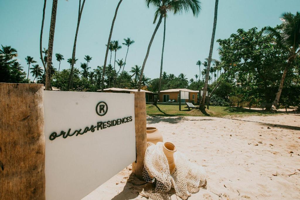 un cartel en una playa con palmeras en el fondo en Orixás Residence en Morro de São Paulo