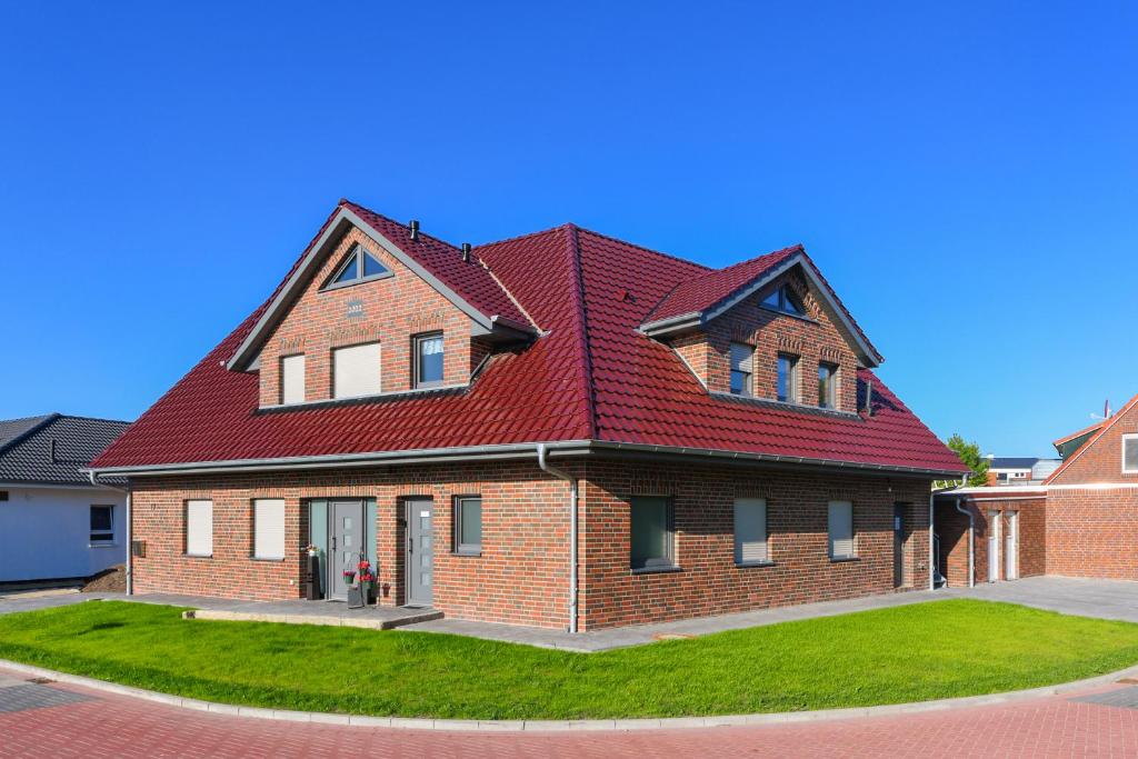 una gran casa de ladrillo con techo rojo en Ferienwohnungen im Haus Deichnest en Bensersiel