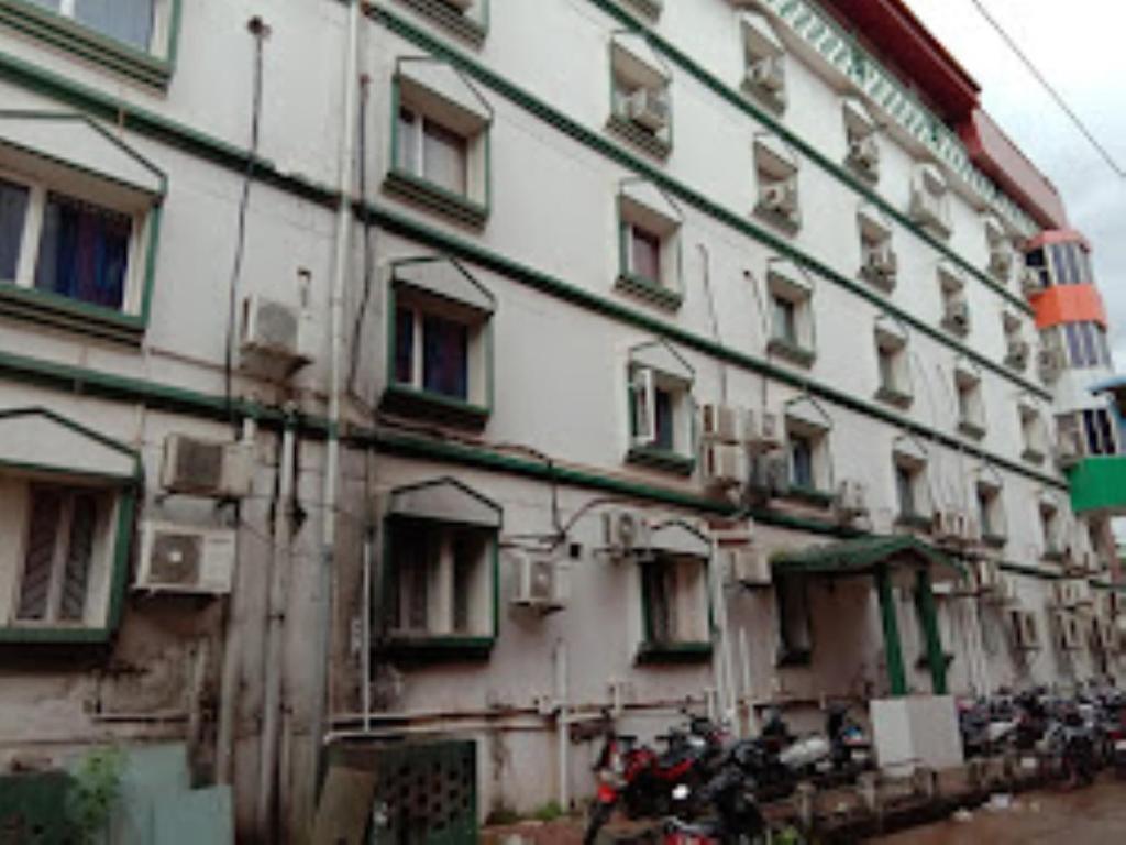 un grand bâtiment blanc avec des motos garées devant lui dans l'établissement Hotel Delmon,Bhubaneswar, à Bhubaneswar