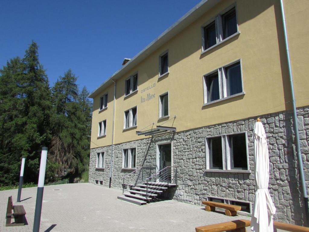 a large building with a bunch of benches in front of it at Ostello La Mine in Cogne