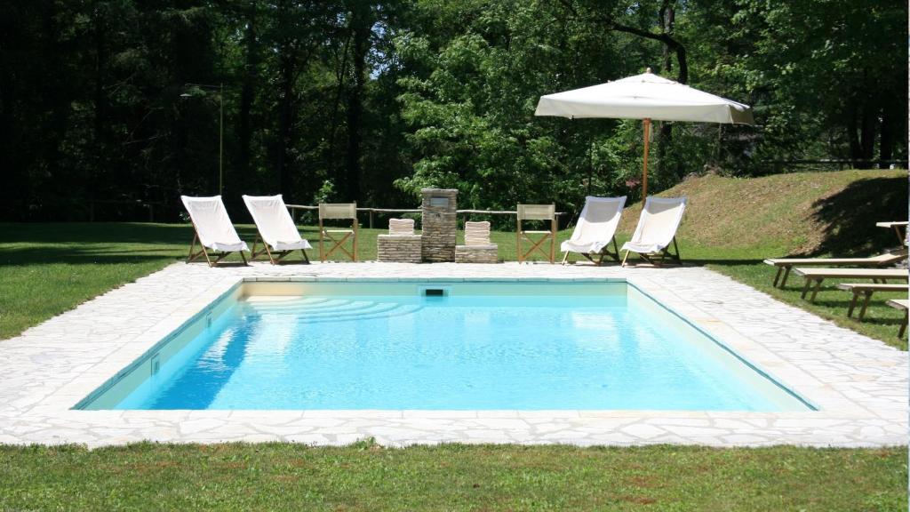 a swimming pool with chairs and an umbrella at Ai Torchi Vecchi in Fivizzano