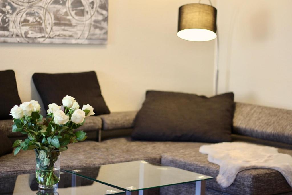a living room with a couch and a glass table with flowers at FeWo Louisa in Sipplingen