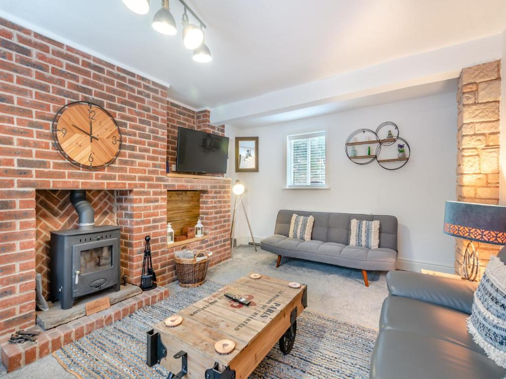 a living room with a brick fireplace and a couch at Poulter Cottage in Elkesley