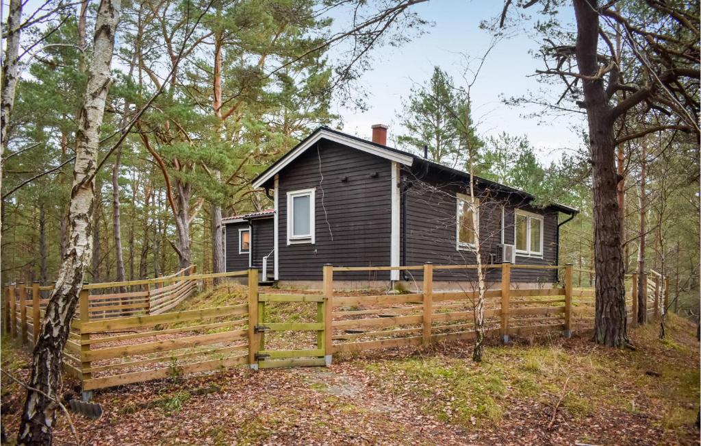 a black cabin in the woods with a wooden fence at Awesome Home In Yngsj With House A Panoramic View in Yngsjö