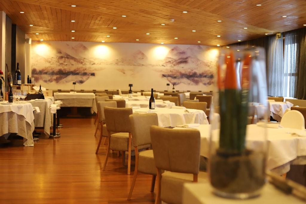 un restaurante con mesas y sillas blancas y una pantalla grande en Style Hotel Grifone, en Madonna di Campiglio