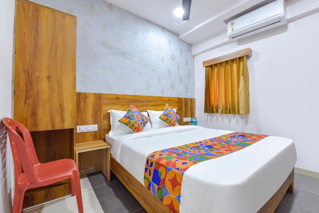 um quarto com uma cama e uma cadeira vermelha em FabHotel Star em Ahmedabad