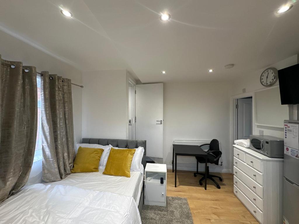 a bedroom with a bed with yellow pillows and a desk at 1st Studio Flat With full Private Toilet And Shower With its Own Kitchenette in Keedonwood Road Bromley A Fully Equipped Independent Studio Flat in Bromley