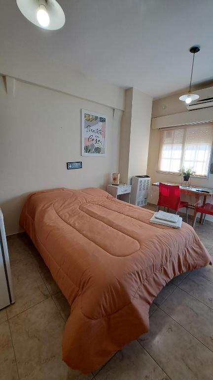 a large orange bed in a room with a table at Center Studio Apartamento en el centro de Trelew in Trelew