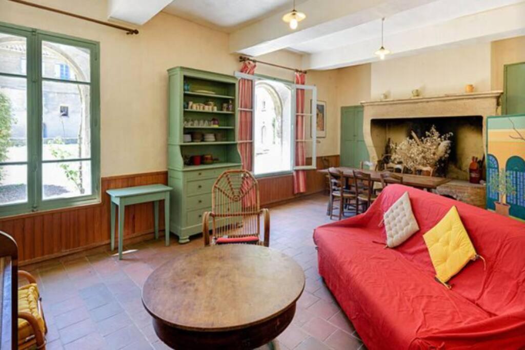 een woonkamer met een rode bank en een tafel bij Château de Teillan - Pigeonnier in Aimargues