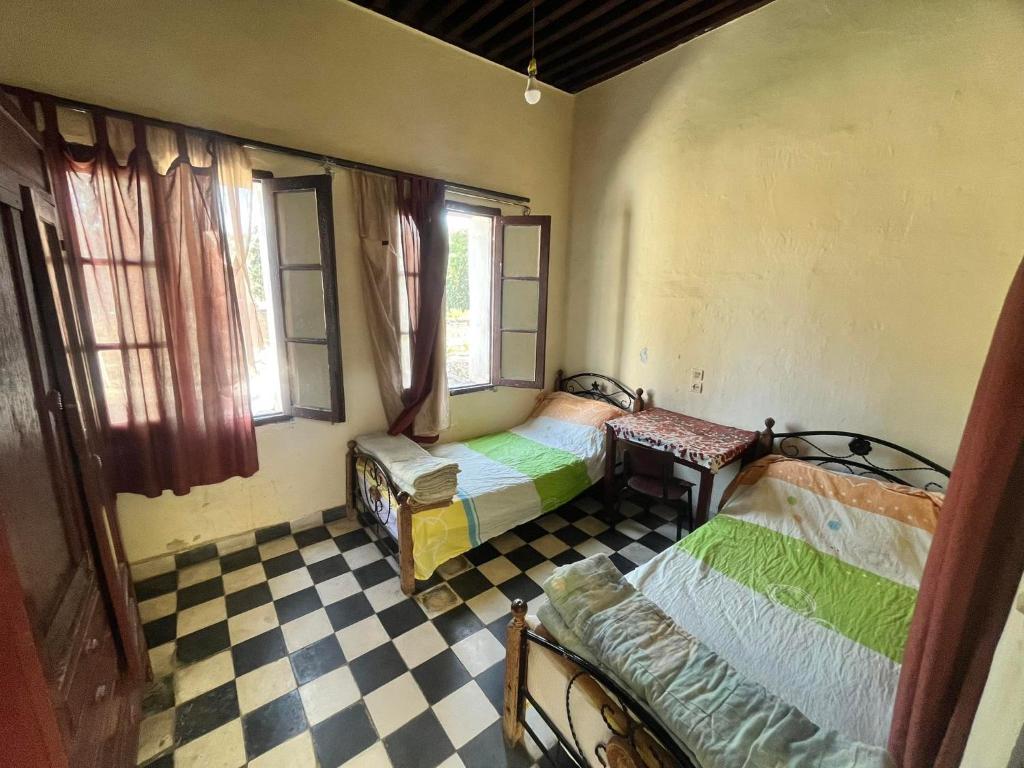 Habitación con 2 camas y suelo a cuadros. en HÔTEL DU PARC, en Fez