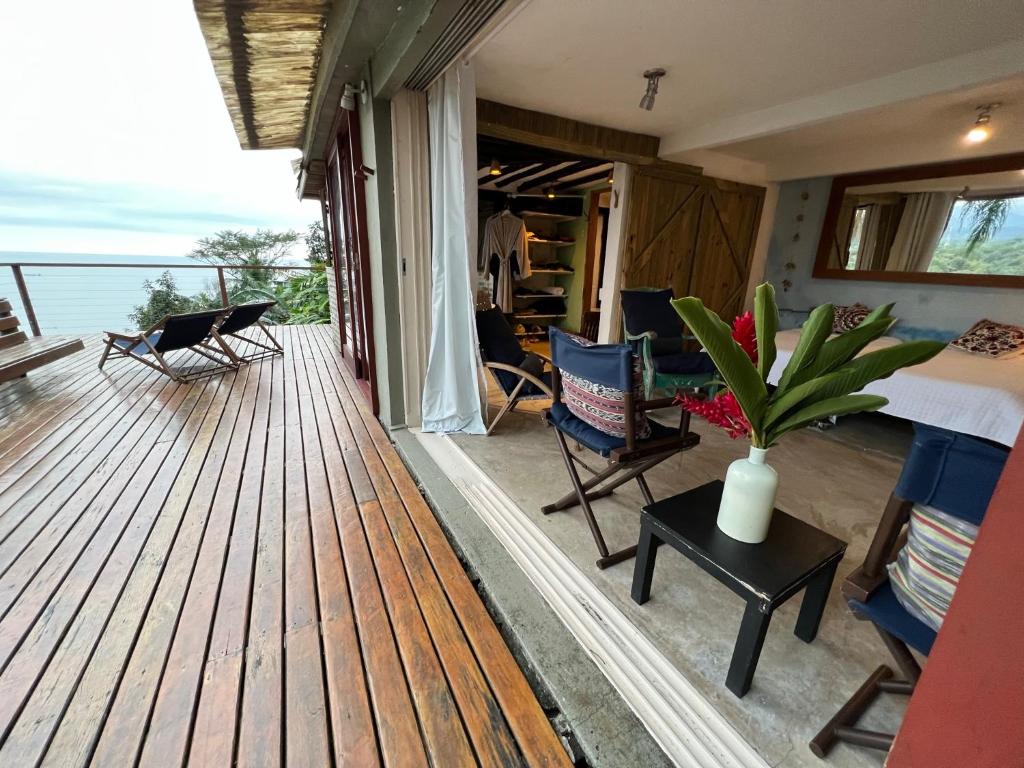 a room with a deck with a bed and chairs at Suíte e sala - Vista Barra do Sahy in São Sebastião