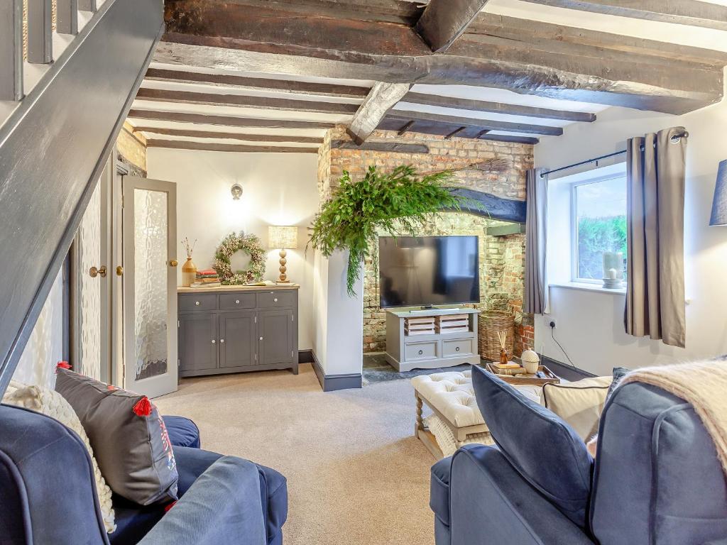 a living room with blue furniture and a kitchen at The Old Smithy in West Ashton