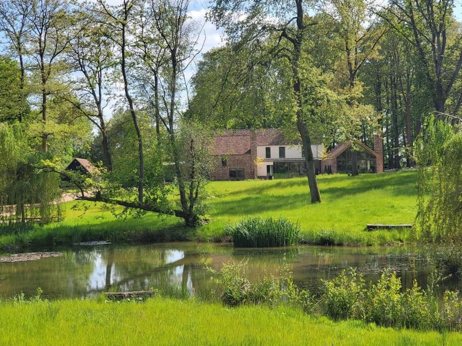 a house in the middle of a field with a pond at Private Apartment at Woodland Retreat in Gamlingay