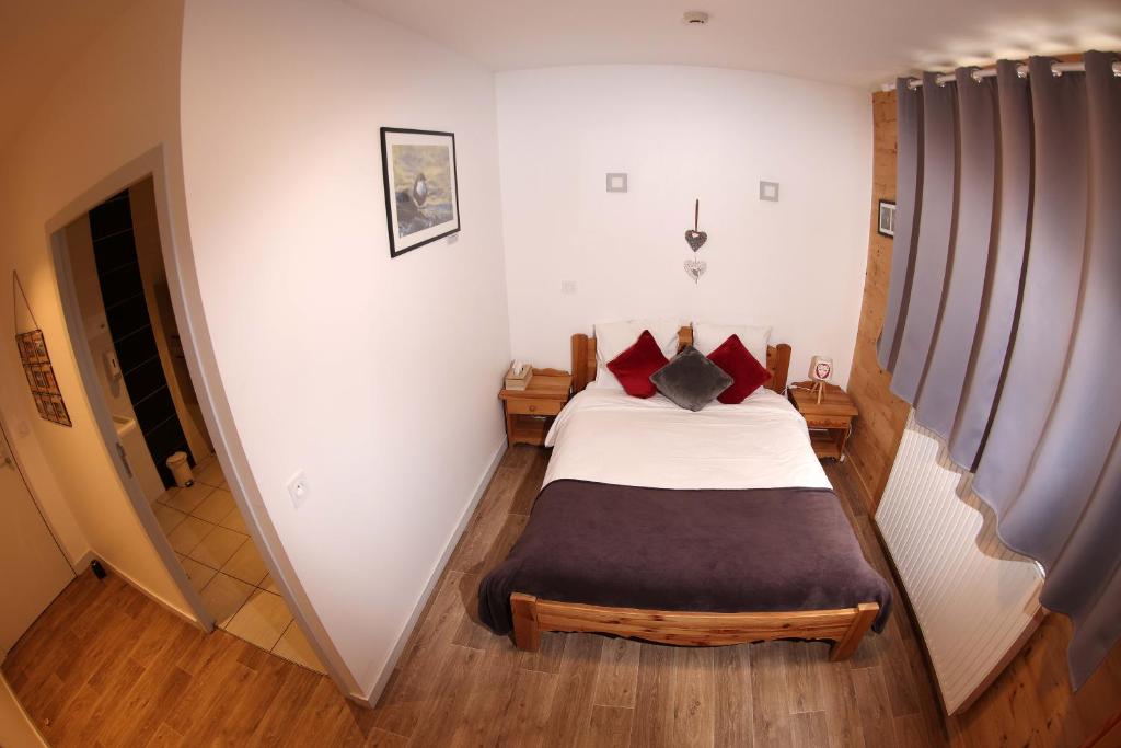 a small bedroom with a bed with red pillows at Le Chalet de la Source in Mouthe