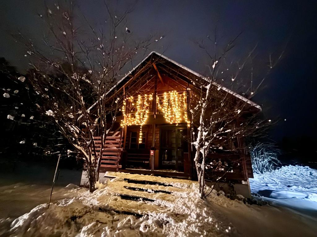 a cabin covered in christmas lights in the snow at Aki in Hakuba