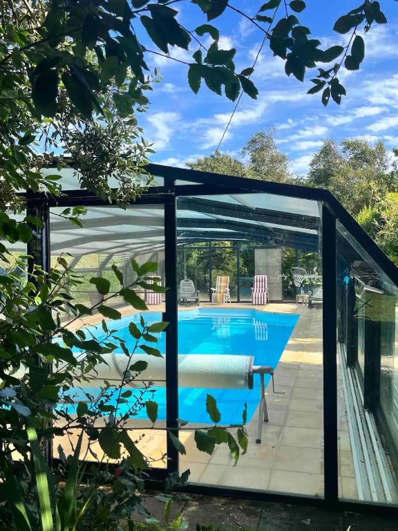 a pool house with a glass door and a swimming pool at Maison 6 personnes avec piscine in Le Conquet