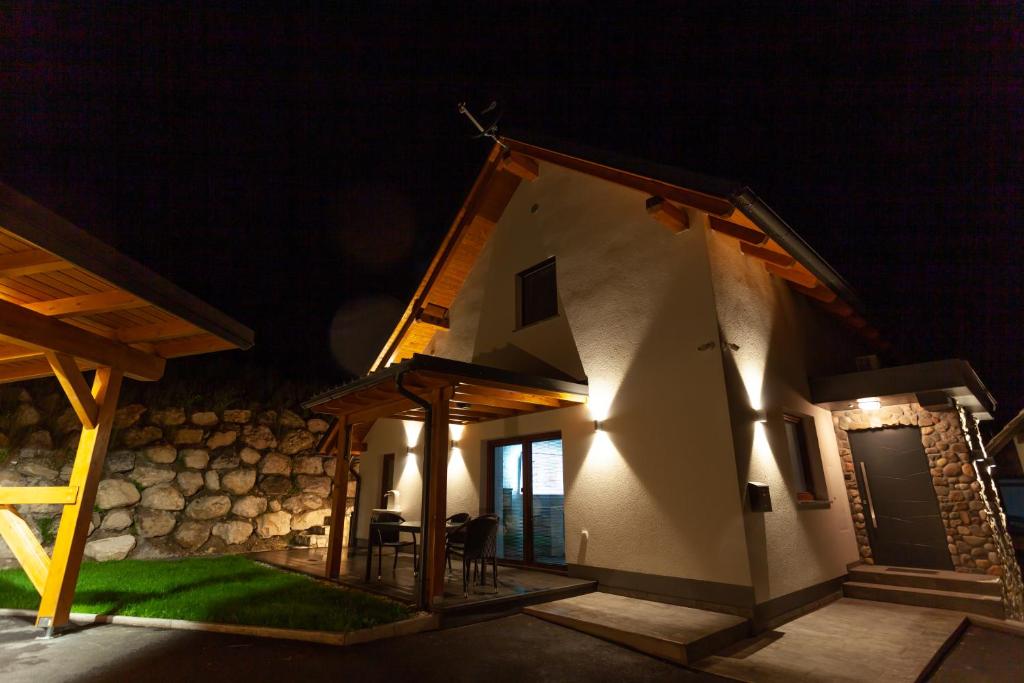 uma pequena casa à noite com uma mesa e cadeiras em MY TIME Holiday House with sauna em Zgornje Gorje