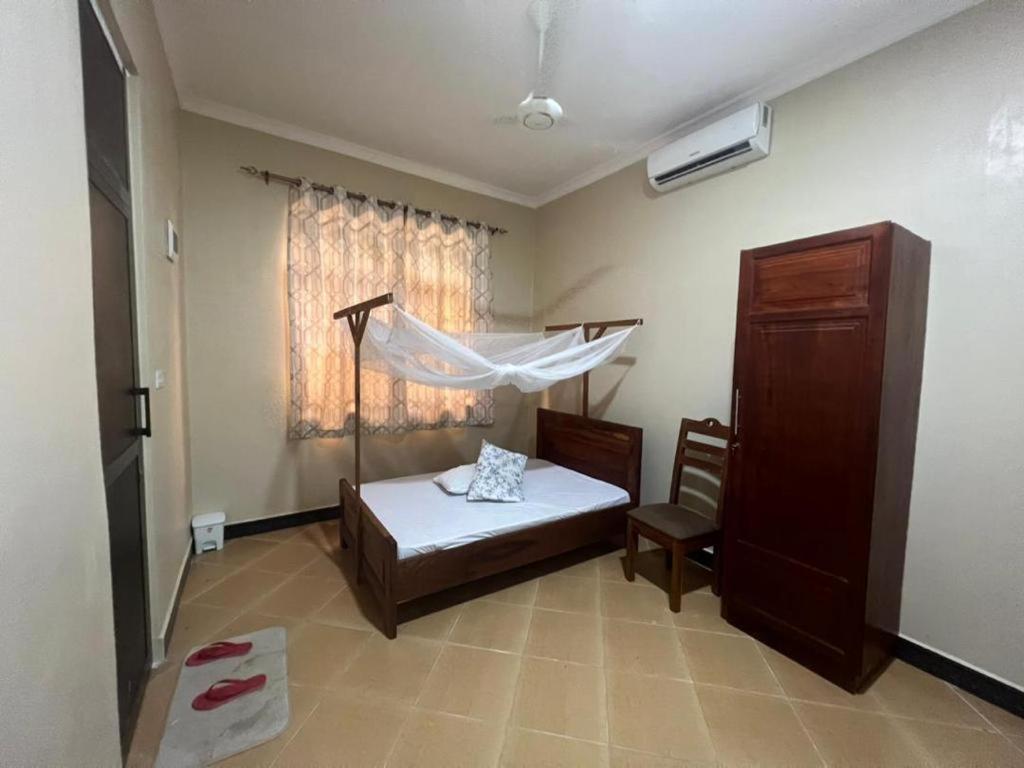 1 dormitorio con 1 cama y ventana con mosquitera en J & S LUGALLA HOUSE, en Dar es Salaam
