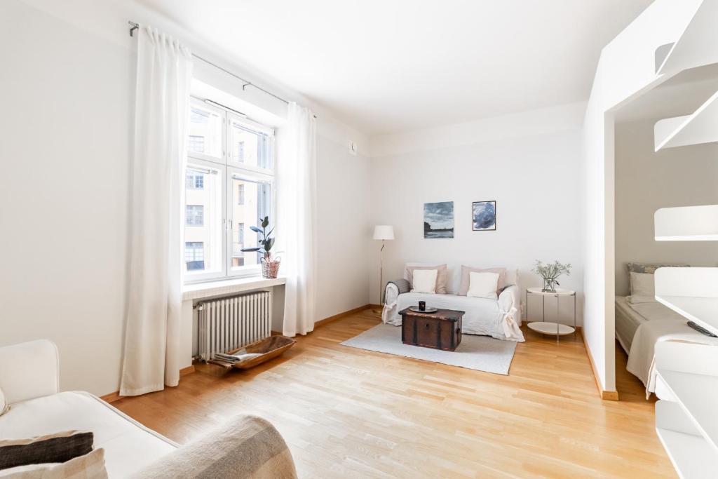 a living room with white furniture and a large window at Cozy, spacious and calm apartment central Helsinki in Helsinki