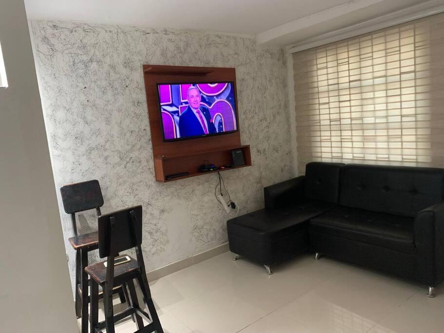sala de estar con sofá negro y TV de pantalla plana en Vivamar Oasis Cartagena, en Cartagena de Indias