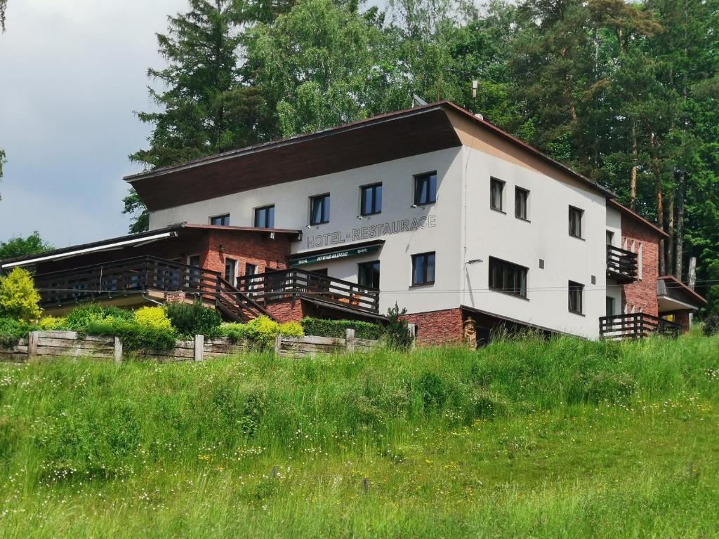 ein weißes Gebäude mit einem braunen Dach auf einem Feld in der Unterkunft Hotel Styl Hlinsko in Hlinsko