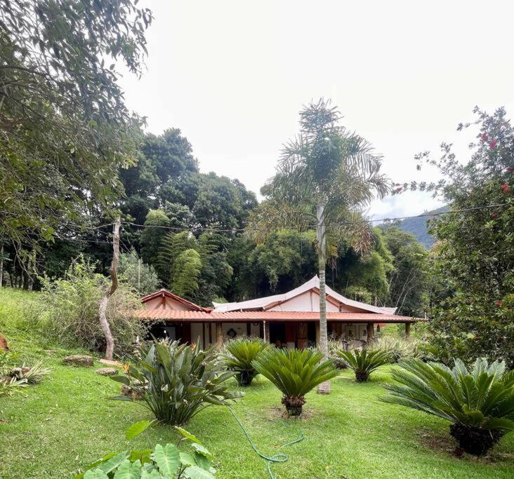 a house in the middle of a field with trees at Casa Portal Sagrado Matutu- Aiuruoca MG in Aiuruoca