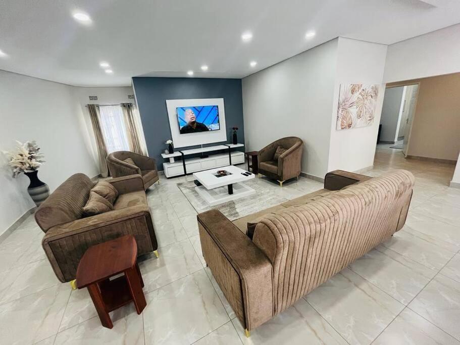 Una gran sala de estar con sofás y un televisor. en Elisheva apartment, en Ndola