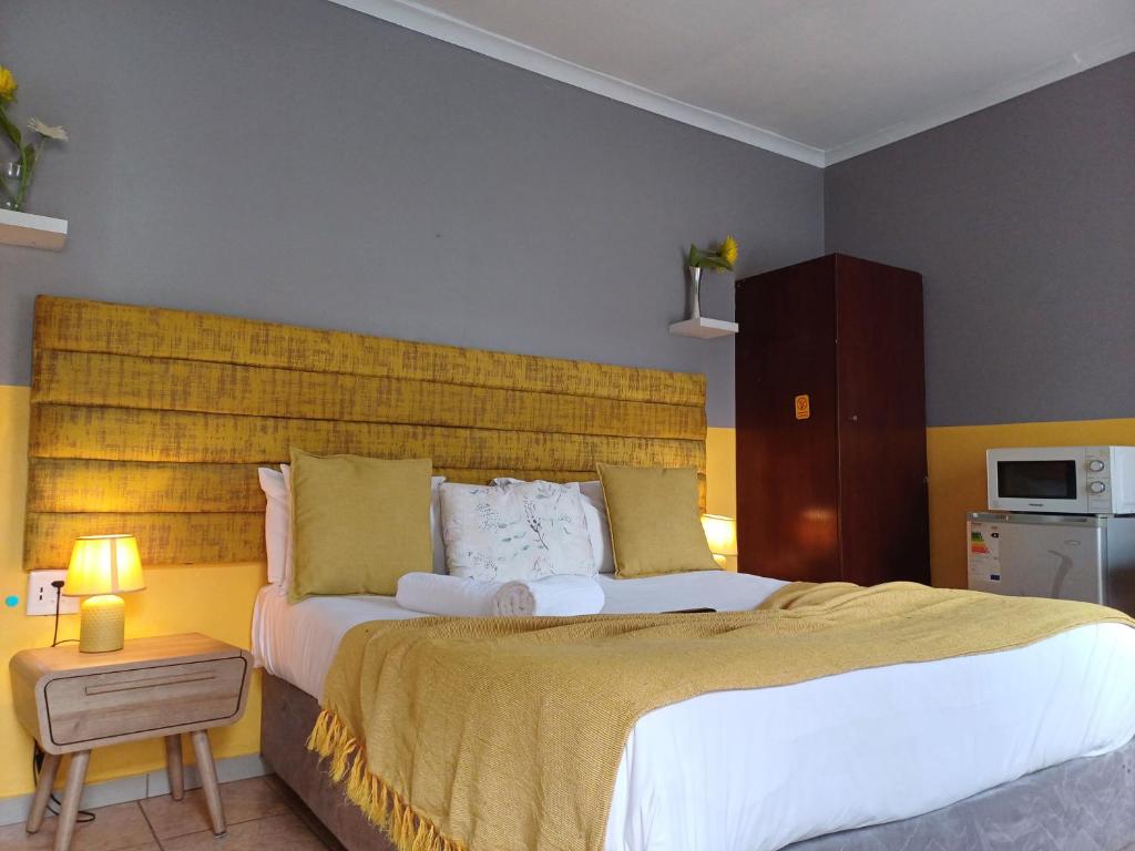 a bedroom with a large bed with a yellow headboard at Horizon Bed and Breakfast in Roodepoort
