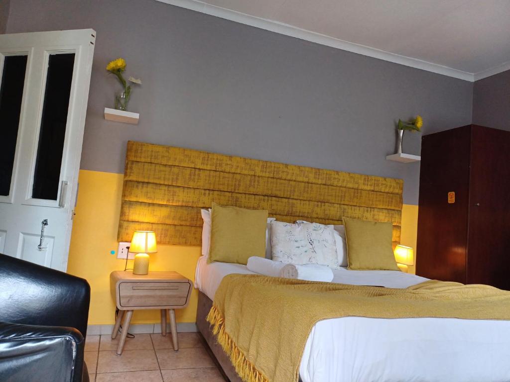 a bedroom with a large bed with a yellow headboard at Horizon Bed and Breakfast in Roodepoort