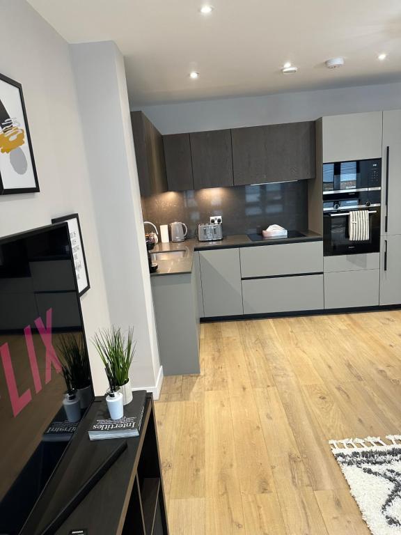 a kitchen with white cabinets and a wooden floor at Richardson Deluxe Apartments (2-Bed) in London
