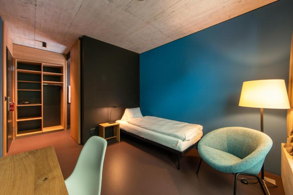ein kleines Zimmer mit einem Bett und einem Stuhl in der Unterkunft 54 Hochgenuss in Schattdorf