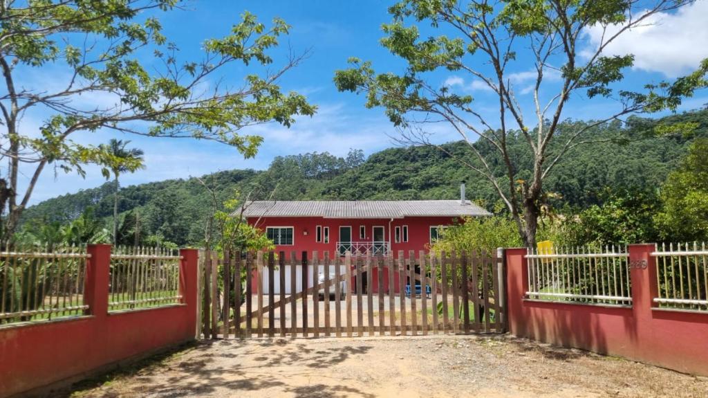 a red fence in front of a red house at Casa no Sítio in Penha