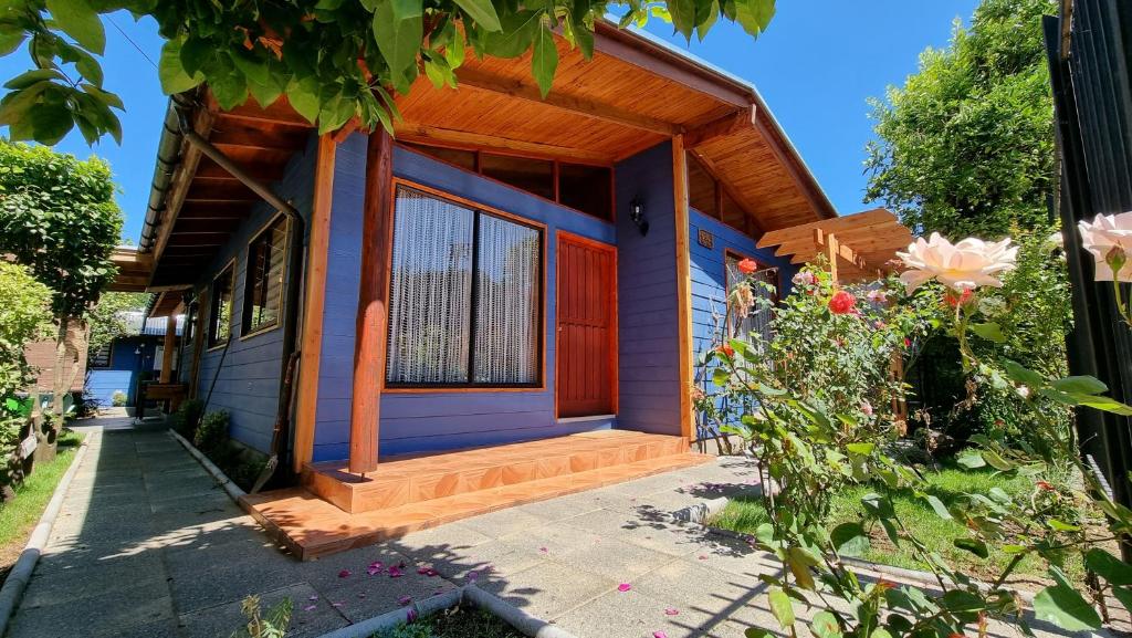 una casa con puerta roja y porche en Blue House Cabaña - Departamento - Habitación en Pucón