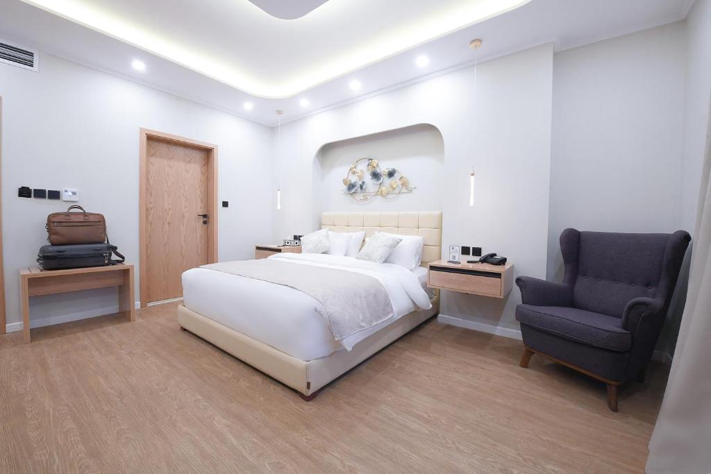 Arabella Premium Residence - New Cairo في القاهرة: غرفة نوم بيضاء بسرير وكرسي