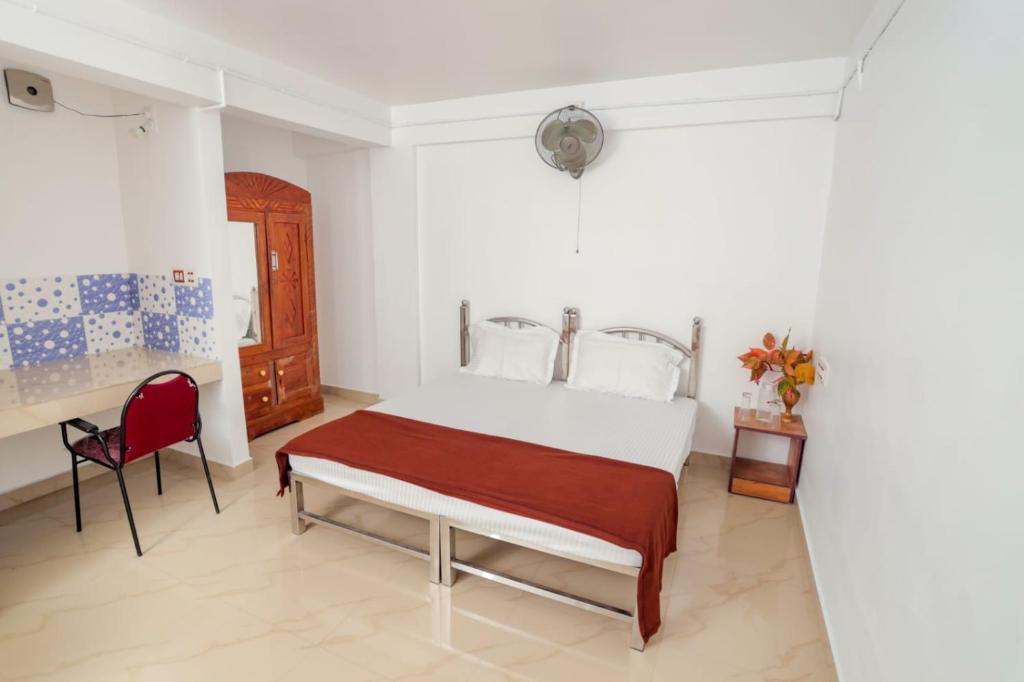 1 dormitorio con 1 cama y 1 silla roja en EL LORA RESlDENCY, en Munnar