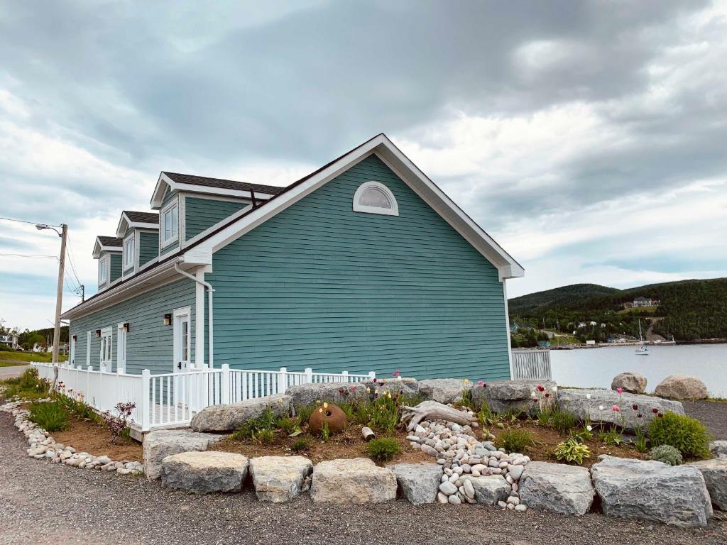 a blue house with a white fence in front of it at Gros Morne BaseCamp in Norris Point