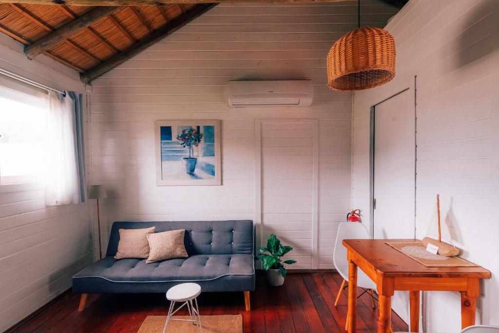 uma sala de estar com um sofá azul e uma mesa em Bon Amour Punta del Diablo em Punta Del Diablo