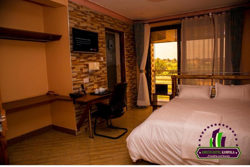 a hotel room with a bed and a desk and a window at Amicus Hotel Kampala in Kireka