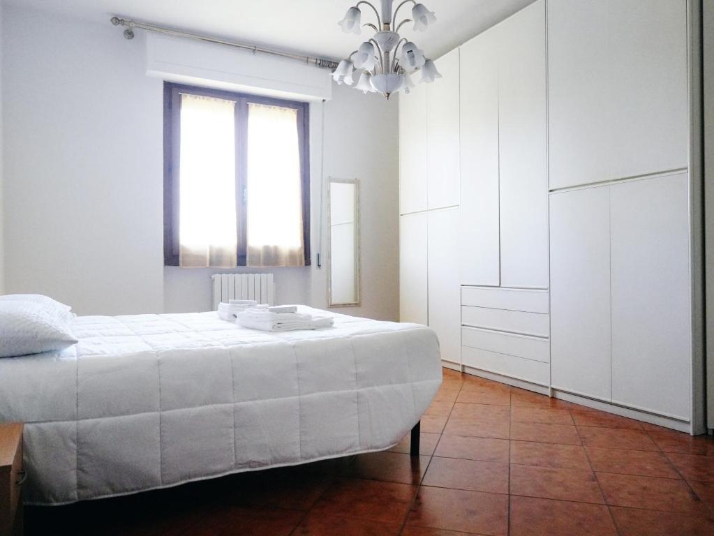 a white bedroom with a bed and a chandelier at A casa di Titti Arezzo in Arezzo