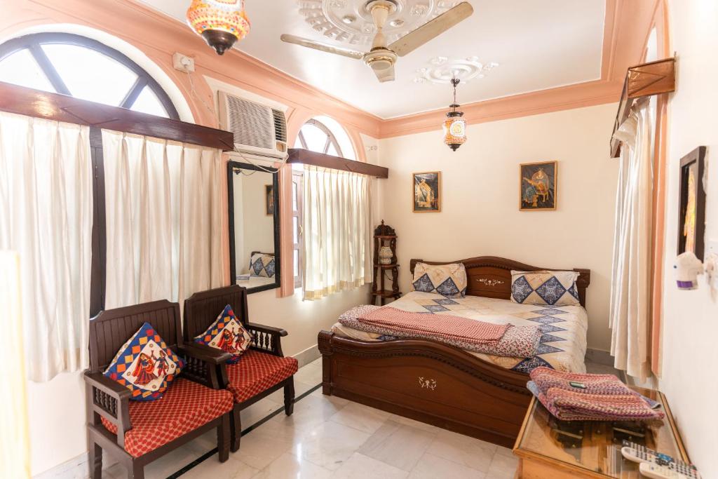 a bedroom with a bed and two chairs in it at Kanhaia Haveli in Pushkar