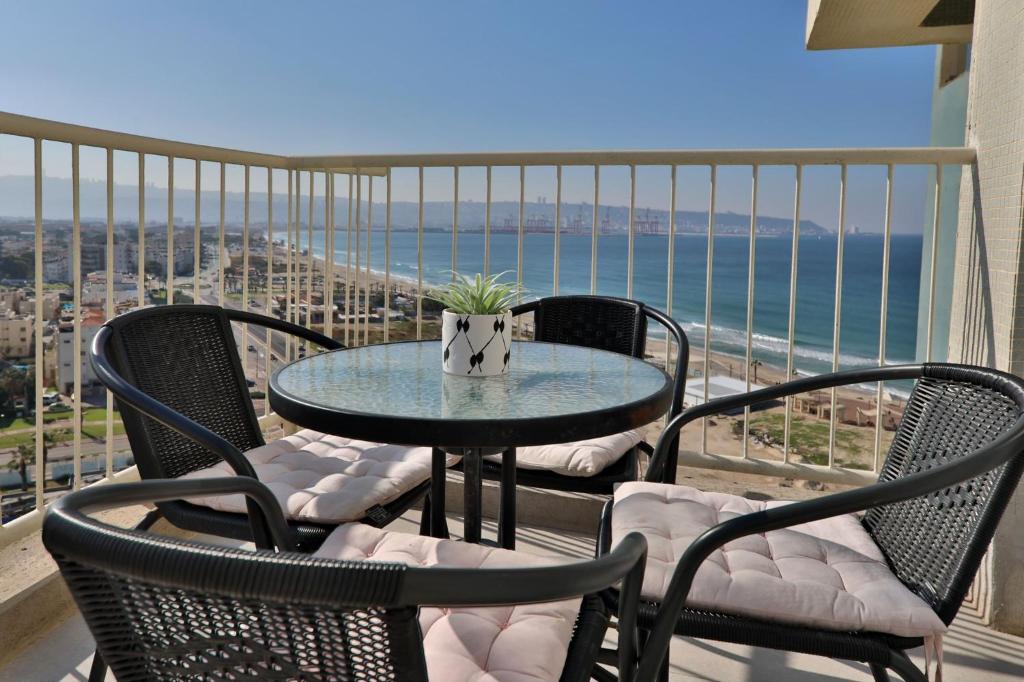 a table and chairs on a balcony with the ocean at דירות קו ראשון לחוף - Apartments First line to the Beach in Qiryat Yam