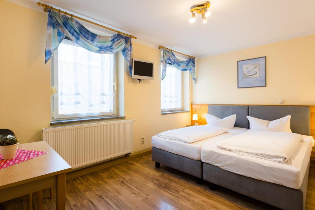 ein Schlafzimmer mit einem großen Bett und zwei Fenstern in der Unterkunft Pension & Ferienwohnungen Töpferstüb'l in Saalfeld