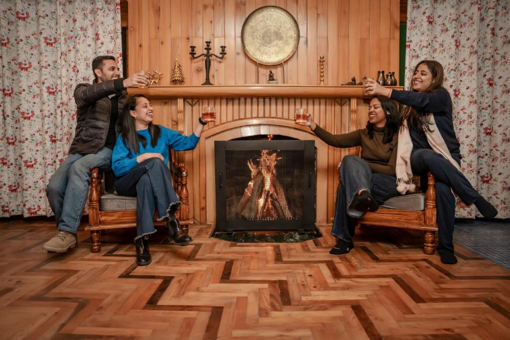 a group of people sitting in a living room holding up a bar at The Wooden Chalet, Manali by DBP in Manāli