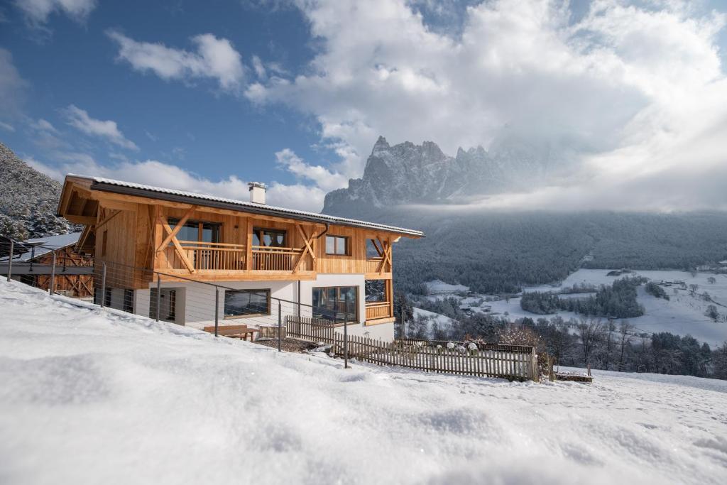 drewniany dom na szczycie pokrytej śniegiem góry w obiekcie Oberzerod Apartments w mieście Siusi