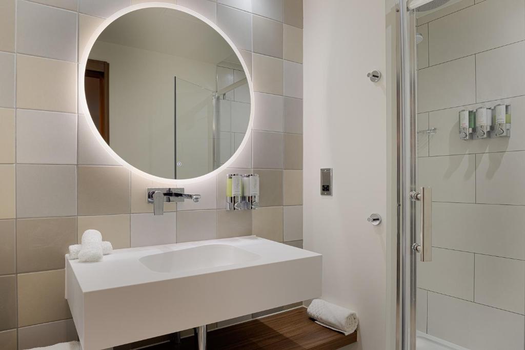 a white bathroom with a sink and a mirror at Hampton by Hilton London Waterloo in London